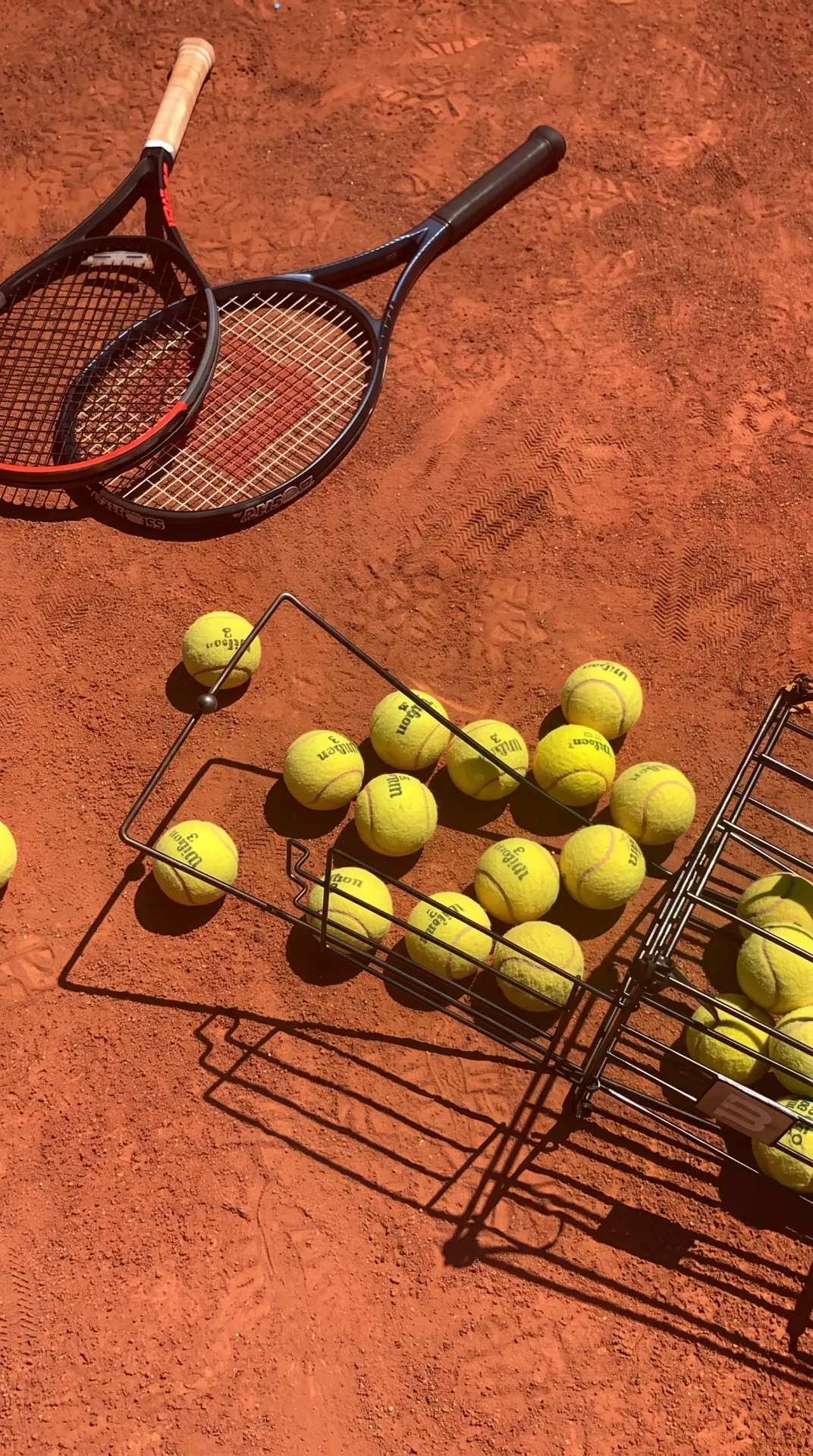Tennis rackets and balls on a clay court